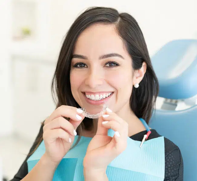 Woman holding a clear Invisalign aligner for teeth straightening in Cary, NC