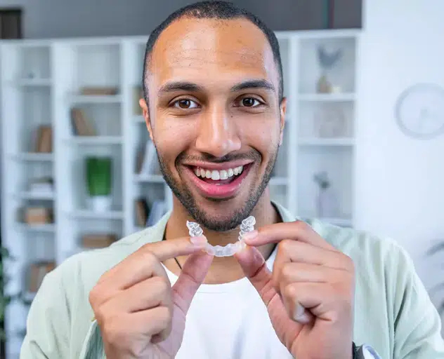 Happy adult patient displaying Invisalign with a confident smile