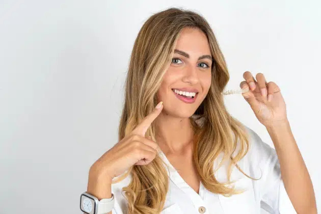 Patient holding transparent Invisalign aligner for a perfect smile
