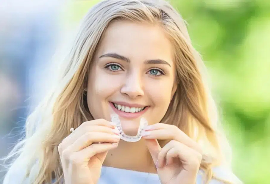 A teenage girl in Cary, NC holding Invisalign and smiling confidently