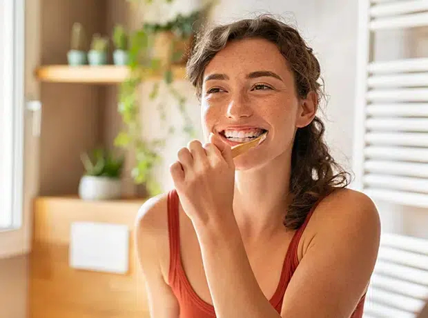 Woman brushing teeth to maintain oral hygiene in Cary NC